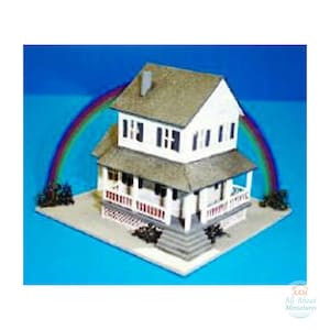 Puede incluir: Un modelo de casa en miniatura de dos pisos de color blanco con techo gris, un porche delantero con barandillas blancas y escalones grises. Un arcoíris colorido se extiende detrás de la casa y el texto AAM All About Miniatures aparece en la esquina.