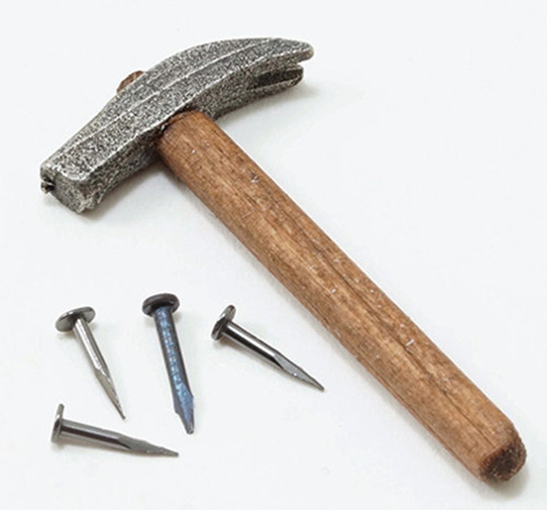 May include: A hammer with a textured, silver-colored head and a wooden handle. Four nails of varying colors and sizes are scattered near the hammer, suggesting a carpentry or construction theme.