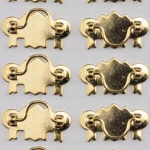 May include: A set of ten gold-colored metal drawer pulls arranged in two vertical columns. Each pull features a decorative backplate with a curved top and a hinged, semi-circular handle attached to two circular mounting points on the plate.