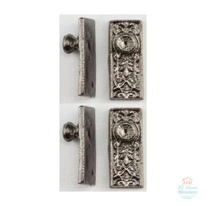 May include: Two sets of miniature silver-toned metal door plates with knobs, each featuring an ornate rectangular backplate with intricate embossed scrollwork patterns and a central circular knob. The text AAM All About Miniatures is visible.