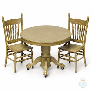 May include: A miniature round wooden dining table with a central pedestal base featuring claw feet on casters, accompanied by two matching spindle-back chairs. The set has a distressed olive-green finish. Includes the logo AAM All About Miniatures.