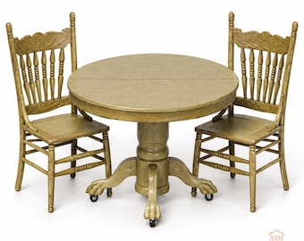 May include: A miniature round wooden dining table with a central pedestal base featuring claw feet on casters, accompanied by two matching spindle-back chairs. The set has a distressed olive-green finish. Includes the logo AAM All About Miniatures.