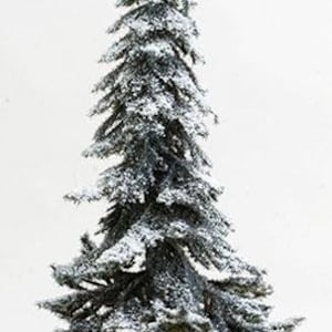 Op de afbeelding: Een miniatuur kunstkerstboom met een besneeuwd uiterlijk. De boom heeft donkergroene naalden en is bestrooid met witte sneeuw. De boom is gemonteerd op een bruine stam.