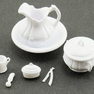 May include: A set of miniature white plastic dollhouse accessories including a pitcher on a basin, a lidded tureen, a small cup, a handled tool, a small lidded container, and a pair of thin, elongated implements with textured edges.