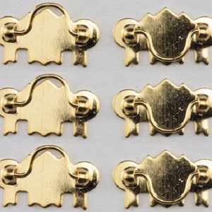 Könnte beinhalten: Sechs goldfarbene Metall-Schubladengriffe mit dekorativem Design. Jeder Griff hat einen Schleifen-Griff und zwei kleine Knöpfe an beiden Seiten.