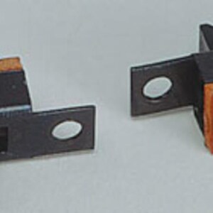 May include: Two black and orange slide switches featuring a rectangular body with a central sliding actuator and two mounting tabs with circular holes on each side. The switches have three metal contact pins extending from the orange base.