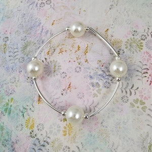 May include: A silver bangle bracelet with four white pearl beads.