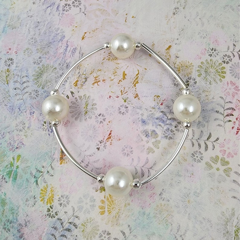 May include: A silver bangle bracelet with four white pearl beads.