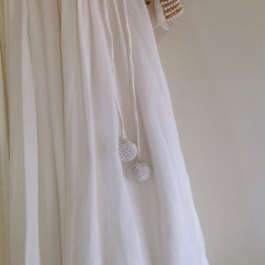 May include: White flowing skirt with a gathered waist and two white beaded tassels.