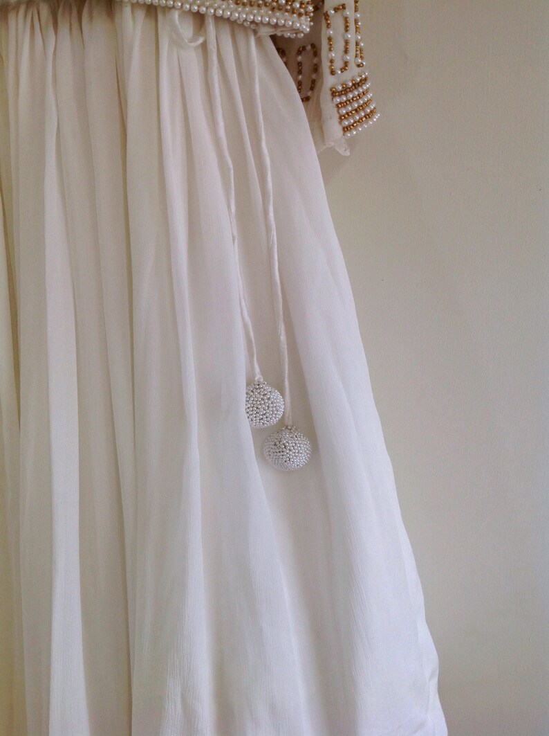 May include: White flowing skirt with a gathered waist and two white beaded tassels.
