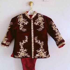 May include: Burgundy velvet jacket with gold embroidery and matching pants. The jacket has a mandarin collar and long sleeves.