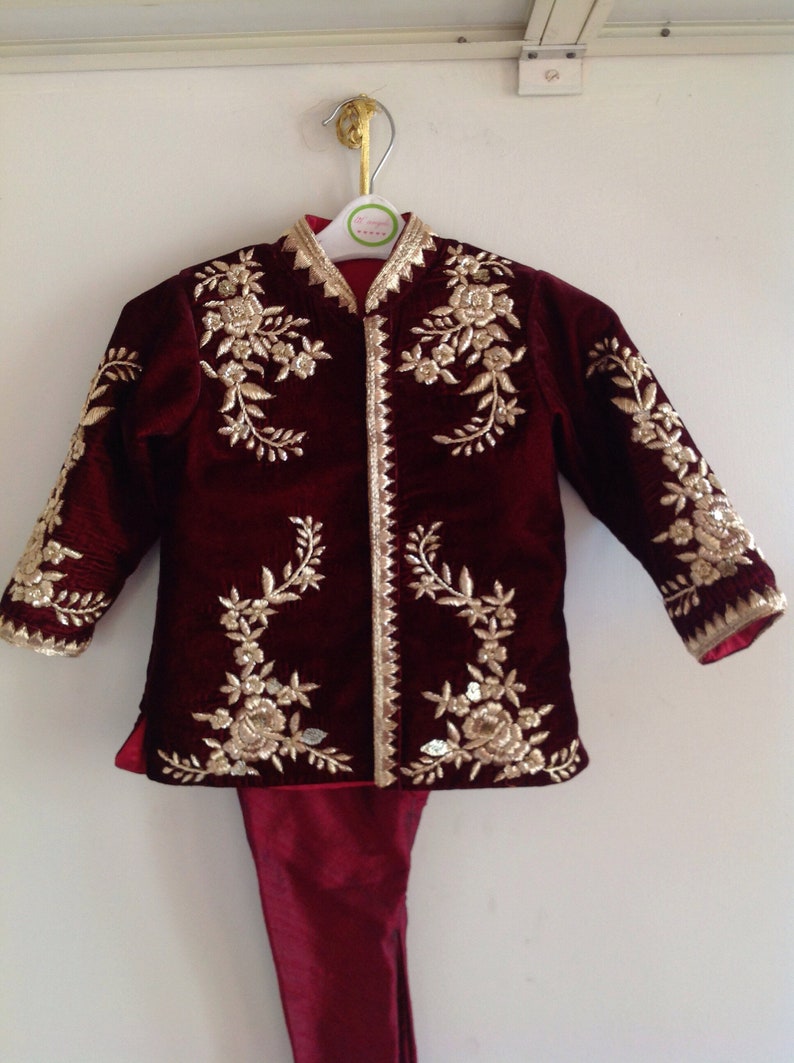 May include: A maroon velvet jacket with gold embroidery and matching pants. The jacket has a mandarin collar and a button closure.