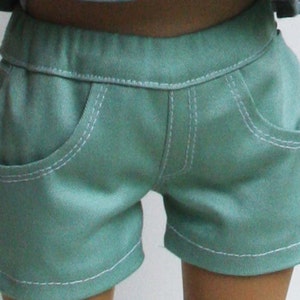 Peut inclure: Short en jean bleu sarcelle avec des coutures blanches et deux poches sur le devant.