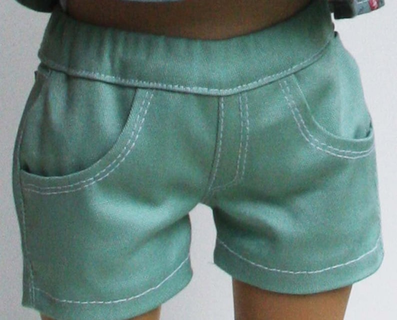 Peut inclure: Short en jean bleu sarcelle avec des coutures blanches et deux poches sur le devant.