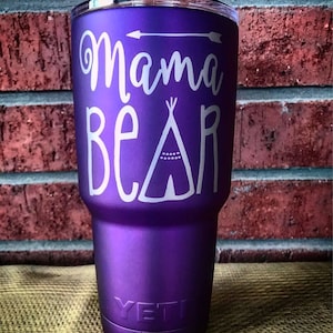 May include: Purple Yeti tumbler with a white design that says "Mama Bear" and a teepee with a white arrow above it.