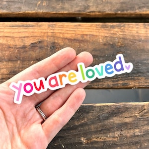 May include: A rainbow sticker with the text "You are loved" and a small heart.