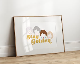May include: A white framed print with a graphic of four women's faces and the text "Stay Golden" in yellow letters.