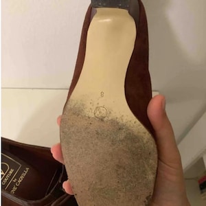 May include: Brown suede high-heeled shoe with a pointed toe. The sole is a light beige color, and the heel is dark brown. The shoe size is 8. The shoe is labeled "COUTURE by Rene Caovilla".