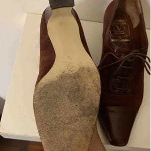 May include: Pair of vintage burgundy suede and leather heeled shoes. The shoes have a pointed toe and lace-up design. The soles show wear. The heel height is approximately 2 inches.
