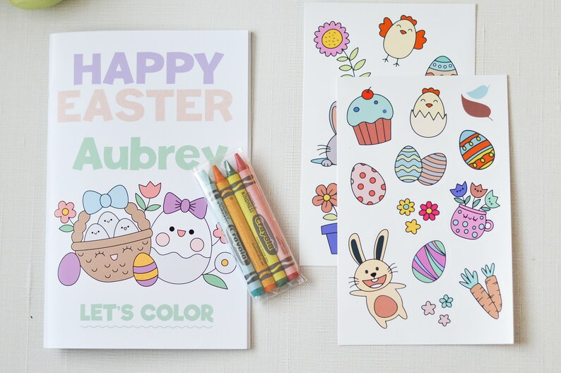 Puede incluir: Un libro para colorear de Feliz Pascua con el nombre Aubrey en la portada. El libro presenta una cesta de huevos y un pollito con un lazo. El libro viene con un paquete de crayones y dos hojas de pegatinas con im&aacute;genes de tem&aacute;tica pascual.