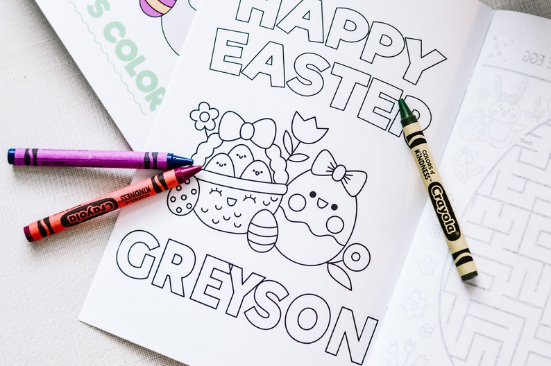 Puede incluir: Una p&aacute;gina para colorear con el texto "Happy Easter" y el nombre "Greyson" en la parte inferior. La p&aacute;gina presenta una cesta de huevos de Pascua con una flor y un solo huevo con un lazo. Se muestran crayones Crayola junto a la p&aacute;gina.