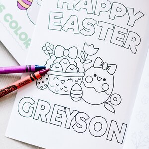 Puede incluir: Una p&aacute;gina para colorear en blanco y negro con el texto "Happy Easter Greyson". La p&aacute;gina presenta una cesta de huevos con una cara linda y un solo huevo con un lazo y una cara linda. Dos l&aacute;pices de colores est&aacute;n en la p&aacute;gina.