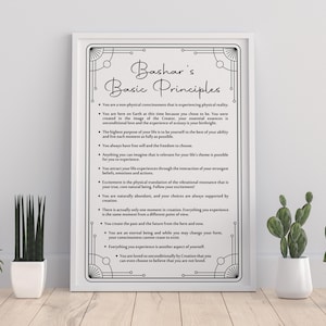 May include: A framed print with the text "Bashar's Basic Principles" in a decorative font. The print is black and white and features a list of principles. The frame is white, and the print is displayed with potted plants.