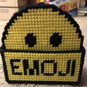 May include: Yellow crocheted tissue box cover with black eyes and the word "ENGUI" in black letters.