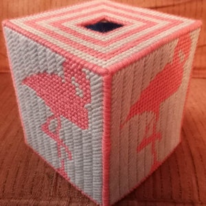 May include: A pink and white tissue box cover with a flamingo design. The cover is made of plastic canvas and is hand-stitched.