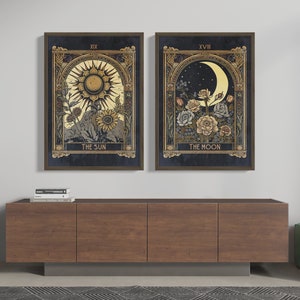 May include: Two framed prints of tarot cards, The Sun and The Moon. The Sun card features a sun with a face and rays, surrounded by flowers. The Moon card features a crescent moon with a face, surrounded by flowers.