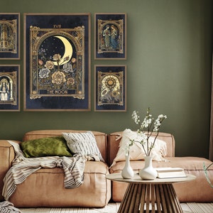 May include: Five framed prints of tarot cards with gold accents and illustrations. The cards are The Tower, The Lovers, The Sun, The Moon, and The High Priestess. The prints are hanging on a green wall above a brown leather couch.