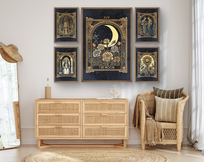 May include: Five tarot cards with gold accents and dark blue backgrounds. The cards are framed and displayed on a wall above a wooden dresser. The cards depict The Tower, The High Priestess, The Moon, The Lovers, and The Sun.