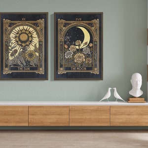 May include: Two framed prints of tarot cards, The Sun and The Moon, with gold accents and floral designs. The Sun card features a yellow sun with rays and the Moon card features a crescent moon with stars.