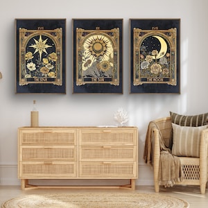 May include: Three framed prints with gold accents and a dark blue background. Each print features a celestial symbol, including a star, sun, and moon, with floral accents. The text below each image reads "The Star", "The Sun", and "The Moon".