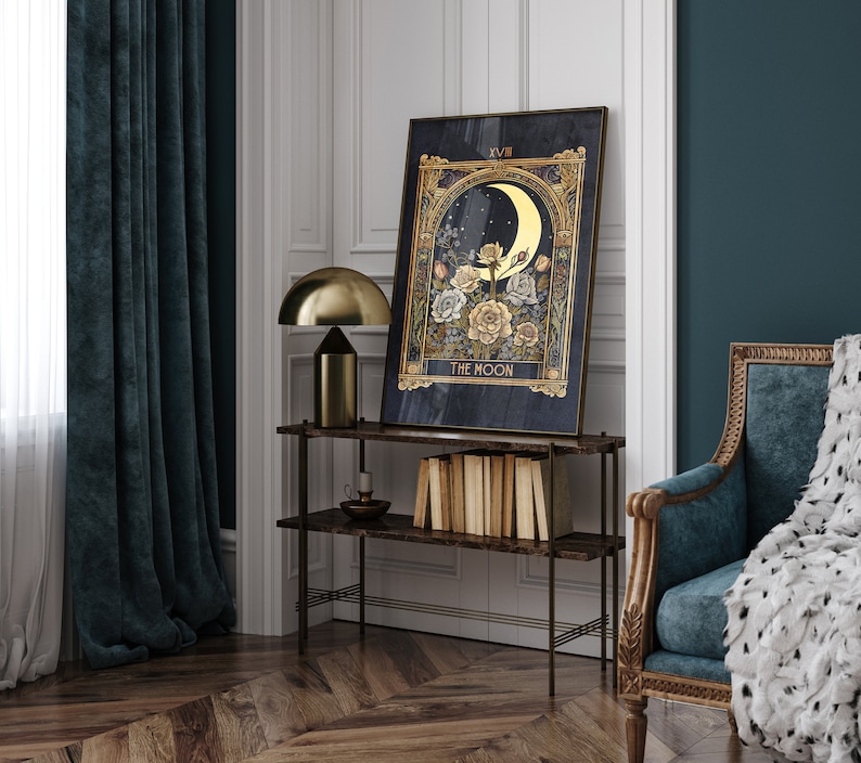 May include: A gold framed tarot card print with a dark blue background. The card depicts a crescent moon with a golden glow and a floral arrangement with white and yellow roses. The card is titled "The Moon" and is framed in a gold frame.