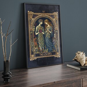 May include: A tarot card with a dark blue background and gold accents. The card depicts two figures, a man and a woman, standing together in a garden. The card is titled "The Lovers" and the Roman numeral "VI" is in the top right corner.