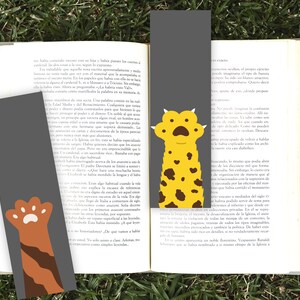 May include: Two gray bookmarks with paw print designs. One bookmark features a brown and orange paw print, the other a yellow and brown paw print.