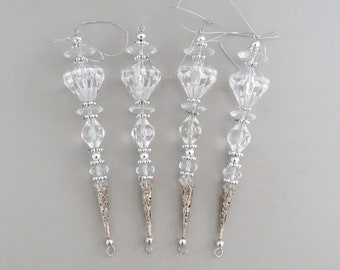 May include: Four silver and clear glass Christmas decorations with a teardrop shape and beaded accents.
