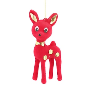 May include: A red reindeer Christmas decoration with gold detailing on the ears and a gold bow tie. The reindeer has gold spots on its body and is suspended by a gold string. The ornament is made of a soft, fuzzy material.