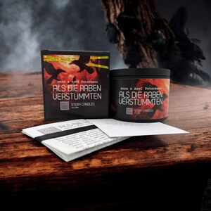 Peut inclure: Un bocal de bougie noir avec une illustration rouge et noire de corbeaux et le texte "Als die Raben verstummten" d'Anna & Axel Petermann. La bougie fait partie d'une ligne de bougies Story Candles. La bougie est à côté d'une boîte avec le même design et le même texte.