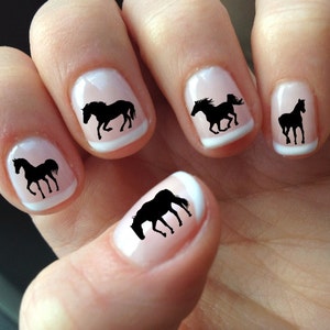 a person holding a white and black manicure with horses on it