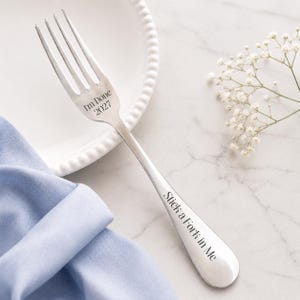 May include: A silver-toned metal fork featuring the engraved text "I'm Done" and "2027" on the tines area, with the additional engraved phrase "Stick a Fork in Me" running vertically along the handle of the utensil.