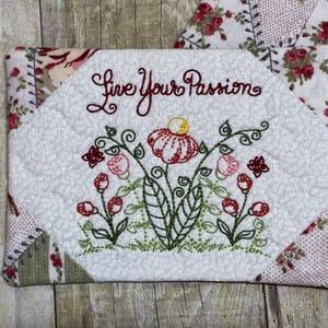 Könnte beinhalten: Ein gestepptes weißes Stoffstück mit floraler Stickerei und den Worten "Live Your Passion" in Burgunderrot. Die Stickerei zeigt rote und rosa Blumen mit grünen Stielen und Blättern. Der Artikel ist von Stoff mit floralem Muster umgeben.