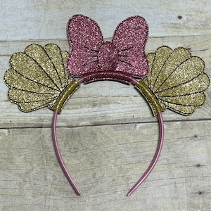 May include: A pink headband with gold glitter seashells and a pink glitter bow.