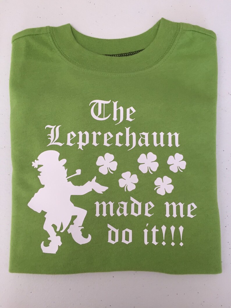 May include: Green t-shirt with a white silhouette of a leprechaun and the text "The Leprechaun made me do it!!!"