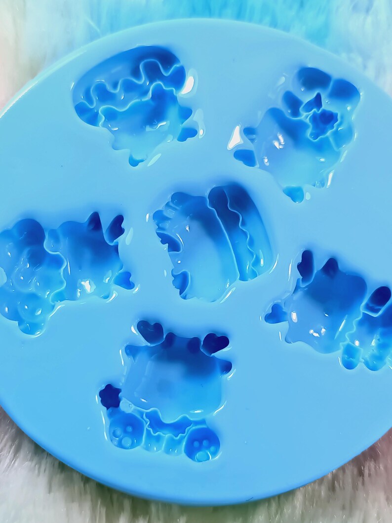 May include: A blue silicone mold with six cavities shaped like cartoon animals. The mold is designed for making small, decorative items.