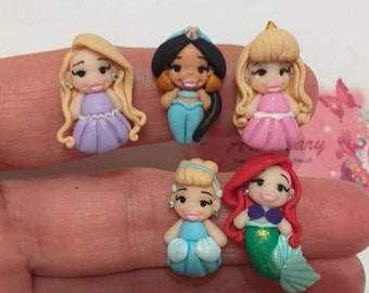 May include: Five miniature Disney princess figurines made of polymer clay. The princesses are Cinderella, Ariel, Jasmine, Belle, and Snow White. Each figurine is about 2 inches tall and has a detailed design.