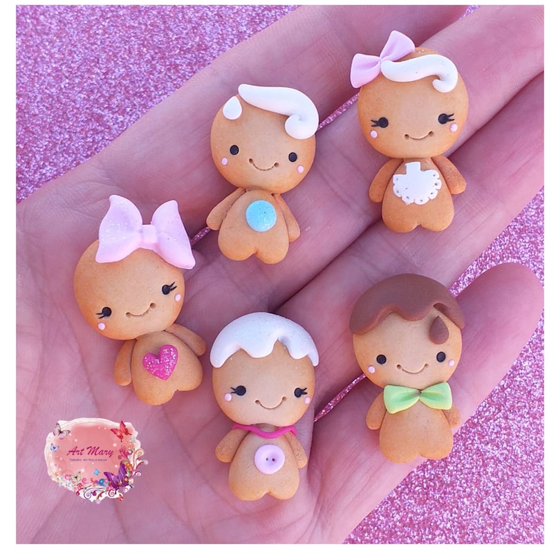 May include: Six gingerbread people figurines made of polymer clay. Each figurine has a different design, including a pink bow, a white bow, a green bow tie, a blue button, a pink heart, and a blue circle.