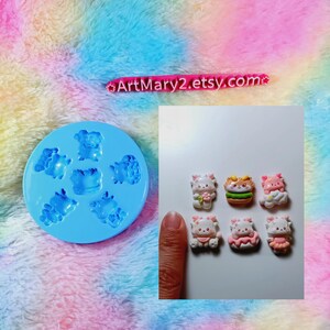 May include: A blue silicone mold with six cavities shaped like cute cartoon animals. The mold is next to six finished resin pieces, each with a different design. The resin pieces are about 1 inch in size.