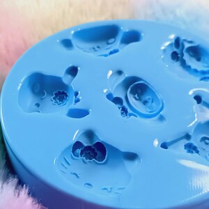 May include: Blue silicone mold with six cavities shaped like cartoon characters. The mold is designed for making small resin crafts.
